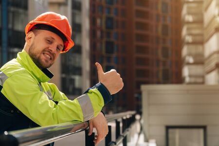 male builder in helmet shows class, holds thumb up. The concept of successful completion of construction. signing a contractの写真素材
