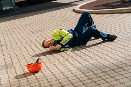 The builder lies down after a leg injury. Industrial accident concept. a young man is having pain in...