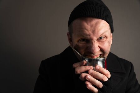 medium plan young homeless man rejoices in a tin can. Unemployed beggar concept. the average plan of a man loafer.の写真素材