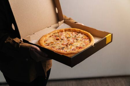 Delicious beautiful whole prosciutto pizza closeup in hands. photo for the delivery site with space for an inscription.の写真素材