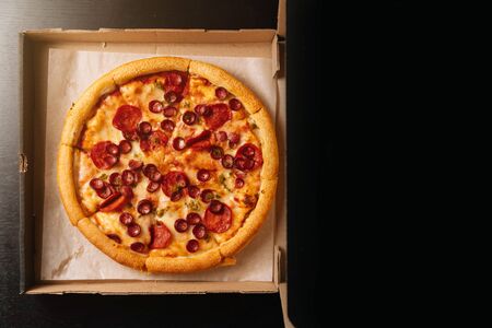 beautiful tasty pepperoni pizza in a paper box on top on a dark background. Fast food delivery.の写真素材