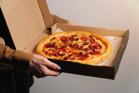 Courier hold beautiful tasty pepperoni pizza top view. Fast food delivery.の写真素材