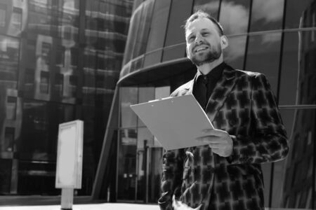The male businessman smiles at the black and white background. The concept of a business conversation against the background of an office buildingの写真素材