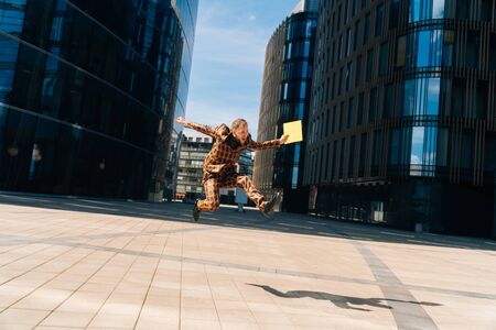 A young Caucasian handsome man joyful with a folder of documents in his hands. A general plan against the backdrop of a blue business center.の写真素材