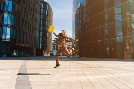 A young Caucasian handsome man joyful with a folder of documents in his hands. A general plan against the backdrop of a blue business center.の写真素材