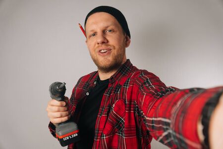 A builder is a man of Caucasian portrait as taking a selfie on a smartphone. The concept of plumbing photography for the blogの写真素材