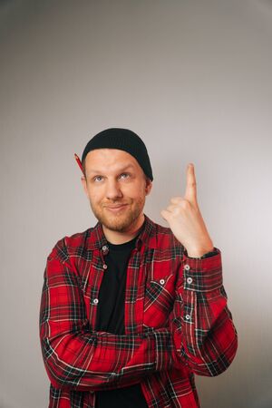 Vertical portrait of a caucasian successful builder, on a light background. a man in a plaid shirt points up.の写真素材