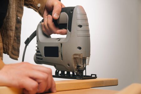 A man uses a tool to saw a tree. The concept of carpentry. Worker in a woodworking workshop.