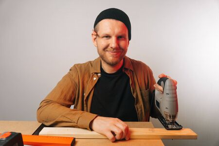 A man uses a tool to saw a tree. The concept of carpentry. Worker in a woodworking workshop.の写真素材