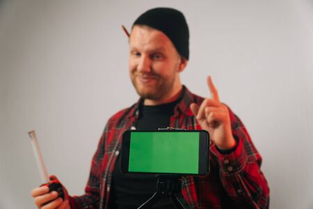 A Caucasian male builder blogger in uniform talks on a smartphone. The concept of a carpenter's video blog in the workshop.の写真素材