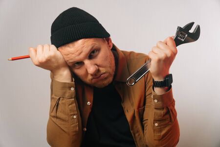 Portrait of a locksmith man holding an adjustable wrench. The concept of a tired worker. call a...