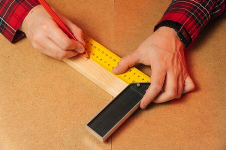 The builder measures a wooden bar in the workplace. The concept of indoor and outdoor carpentry....