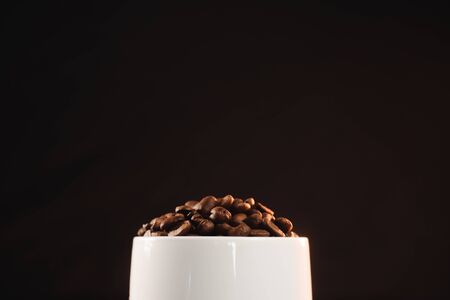 A white coffee cup filled with roasted dark coffee beans. The concept of copying the space for the drinks menuの写真素材