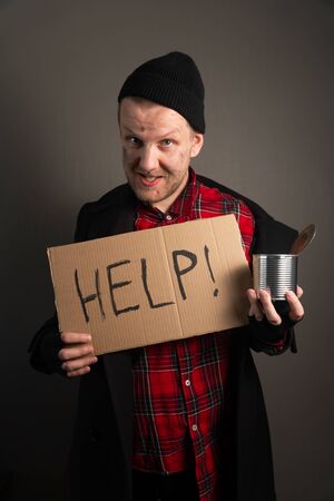 vertical shot of the homeless man holding a cardboard with the inscription in his hands asks for help. begging conceptの写真素材