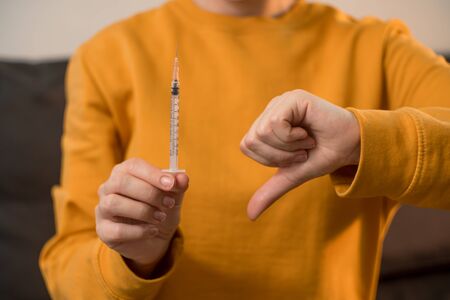 Close up of female hands tearing injection syringe. The concept of unsafe drug administration alone at home without medical assistance.の写真素材
