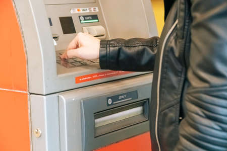 SAINT PETERSBURG, RUSSIA - APRIL 28, 2020 A young woman uses an ATM to get paid. concept of paying...