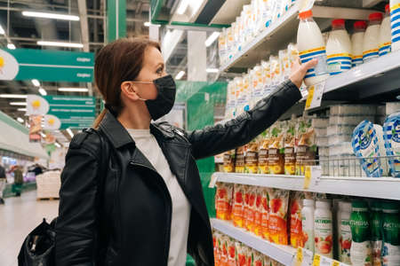 SAINT PETERSBURG, RUSSIA - APRIL 28, 2020 Portrait young Caucasian girl in a medical black mask chooses clothes, shoes products in the supermarket. The concept of social distance andのeditorial素材
