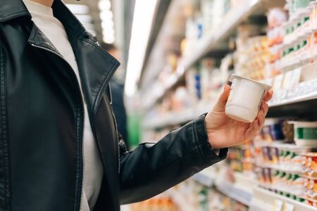 Close-up women's hands hold groceries in the store. The concept of buying fruits and vegetables in a hypermarket during quarantine.の写真素材