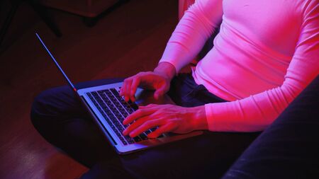 Macro shooting, men's fingers, which print on a laptop, evening muted blue-red light. Work from...