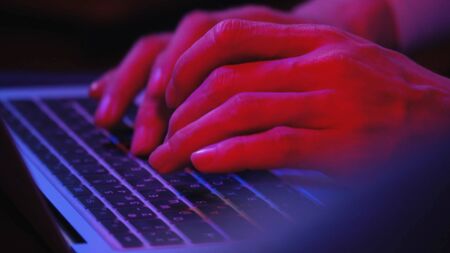 Macro shooting, men's fingers, which print on a laptop, evening muted blue-red light. Work from home, coronavirus pandemic. Shot 4kの写真素材