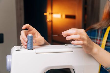 Small business seamstresses, making clothes in his apartment, home workshop. Girl inserts thread...