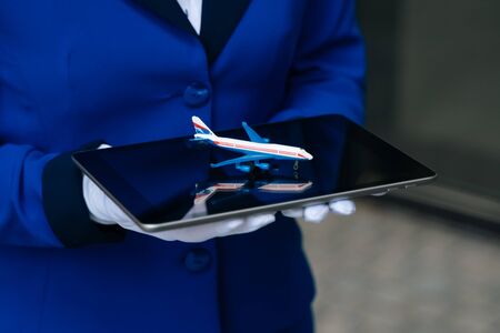 The mini plane's layout is in the hands of a flight attendant in white gloves closeup. The concept of using a toy plane for an airline. High quality photoの写真素材