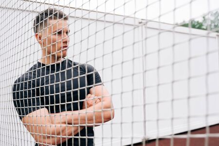 Blurred football net background. A man stands outside the sports gate.
