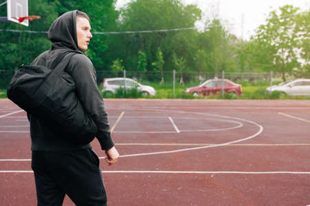 A sporty young man goes with a bag in his hands on the sports ground for strength training.の写真素材