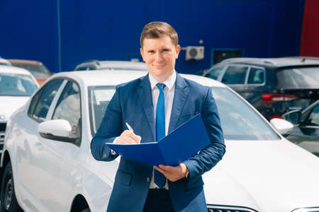 A man stands near the transport. The agent holds the car keys and tablet next to the car.の写真素材
