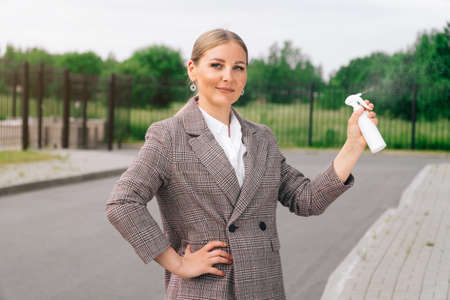 Stylish girl in an elegant suit holds bottle with an antiseptic. The concept of health care during a pandemicの写真素材
