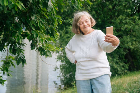 A beautiful European older woman makes a selia. Elderly grandmother talking on videoの写真素材
