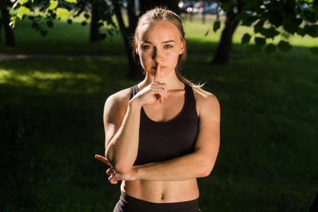 elegant woman holds her hand at the lip. The concept of sign of silence. Warning by an engineer at a construction siteの写真素材