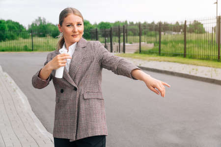 Stylish girl in an elegant suit holds bottle with an antiseptic. The concept of health care during a pandemicの写真素材