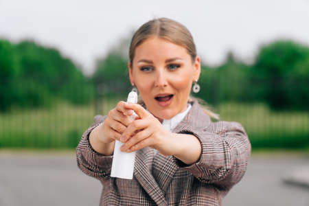 A close-up of a woman holds her mouth open in her hands with a white spray bottle.の写真素材