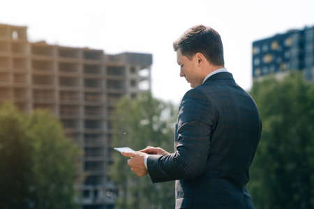 Stylish young man holds a digital tablet against the backdrop of the city background. Theの写真素材