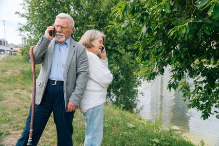 Elderly fashionable couple taking selfie on samrton in the park. Cheerful stylish elderly woman walks in nature.の写真素材