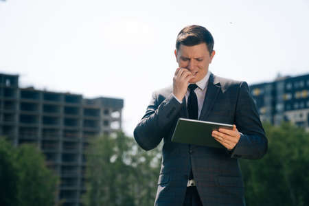 Stylish young man holds a digital tablet against the backdrop of the city background. Theの写真素材