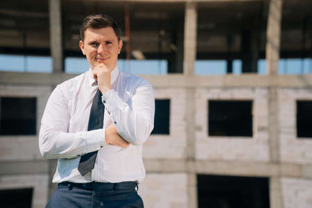 Elegant European man in business clothes against the background of construction.の写真素材