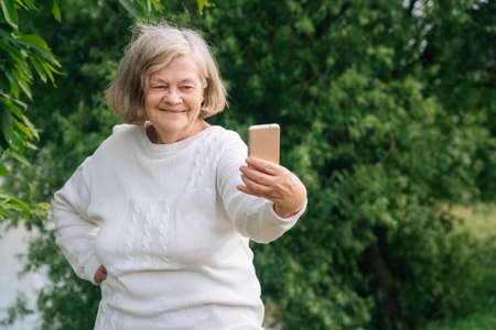Elderly fashionable couple taking selfie on a samrton in the park.の写真素材