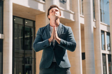 Portrait of a young businessman who prays at a special time. Request for help appealing to Godの写真素材