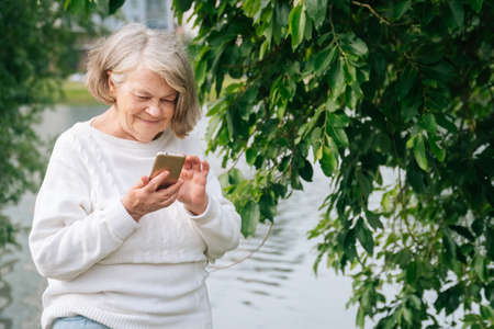 An adult woman speaks on a smartphone. An elderly grandmother holds a phone.の写真素材