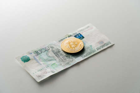 Coin Biktcoin lies on a paper banknote of Russian rubles. Concept of virtual currency in exchange for cashの写真素材