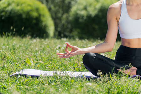 A young Caucasian girl practices yoga meditation outdoors in the park. The concept of peace of mind. Balance and harmony in lifeの写真素材
