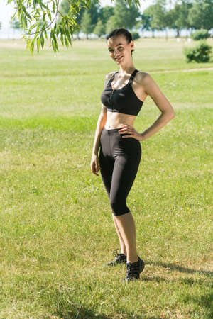 Portrait of a sporty stylish young girl holding a yoga mat in her hands on a summer day at sunset.の写真素材