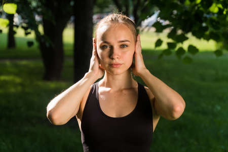 The outdoor sportswoman is surprised. Portrait fitness trainer in shock, close ears with his handsの写真素材