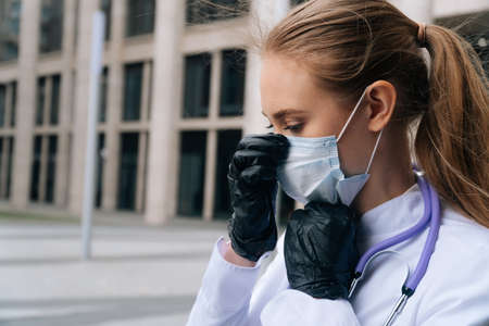 close up of the face of a young female doctor putting on a medical mask with glovesの写真素材
