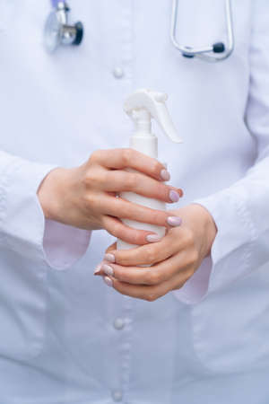 bottle of antiseptic spray in female medical hands closeupの写真素材
