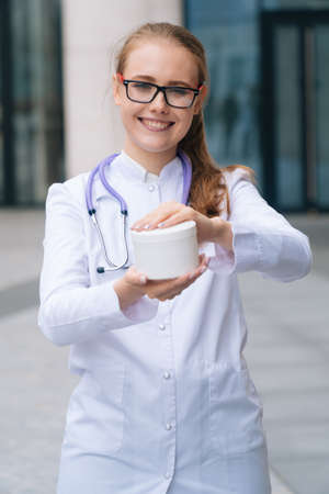 A portrait of a young doctor of a woman holding a jar of creamの写真素材