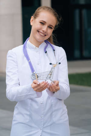 The girl doctor with a stethoscope around her neck holds a shopping cartの写真素材