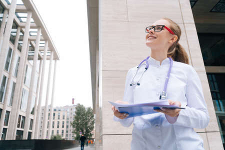 Portrait of an elegant pensive female doctor in glasses, stylish woman in a medical gownの写真素材